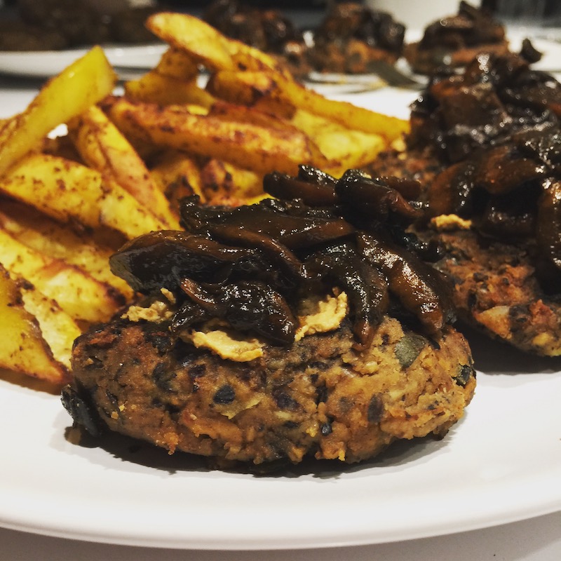 Blackbean Tempeh Burger with fries and smokey mushrooms on white plate, vegan, plantbased