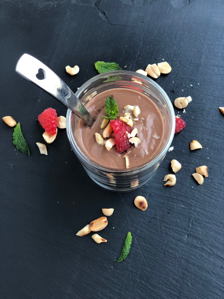 Chocolate Peanutbutter Mousse, vegan, plantbased, shot from top with raspberry on black background with spoon with heart