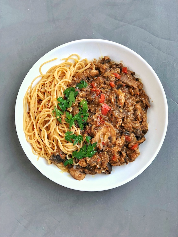 Vegan Smokey Tempeh Eggplant Pasta Sauce with sundried tomatoes plantbased on grey background with parsley