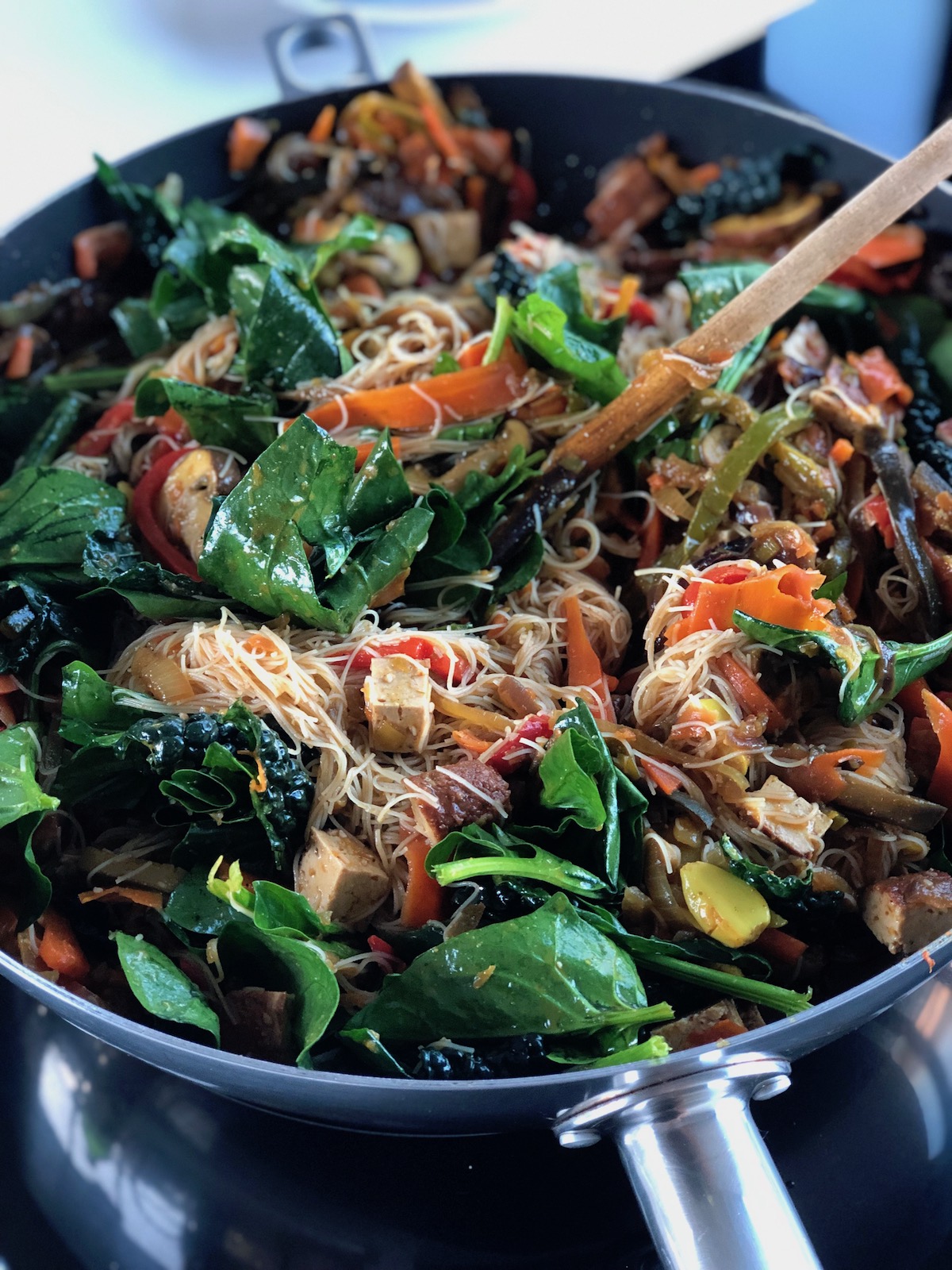 Fideos de arroz con verduras y espinacas en un wok