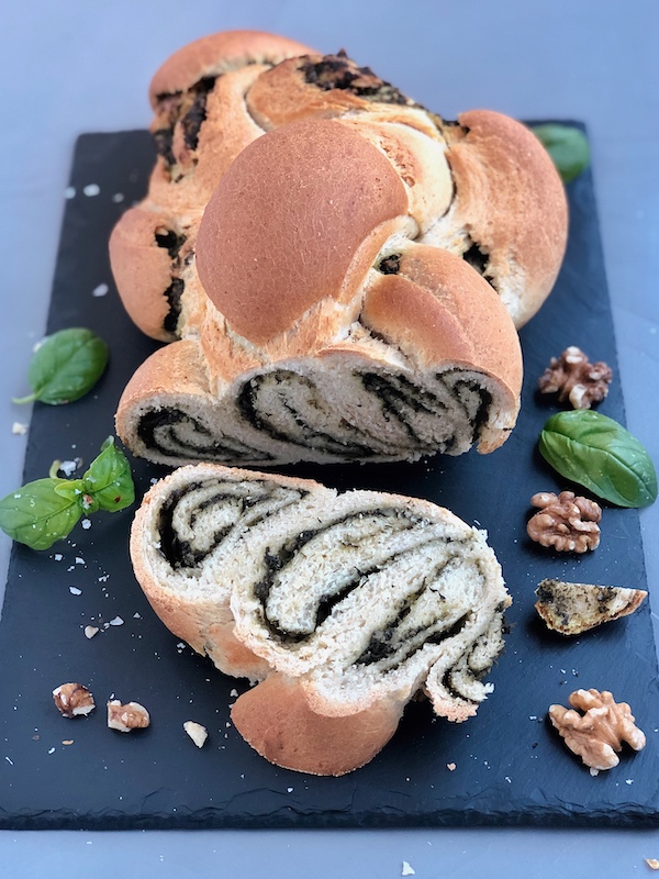 Braided Bread with Superfood Pesto on black slate with walnuts and basil leaves