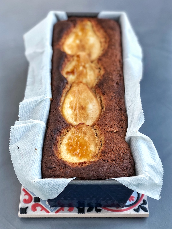 Lemony Olive Oil Banana Bread with vanilla, almonds and caramelized pears on top on ceramic plate