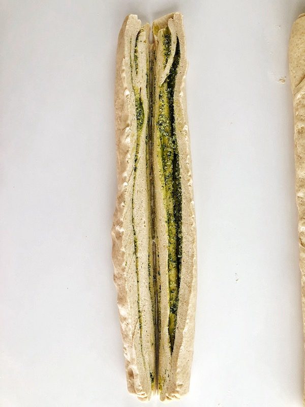 Raw dough roll of vegan twisted pesto bread sliced open